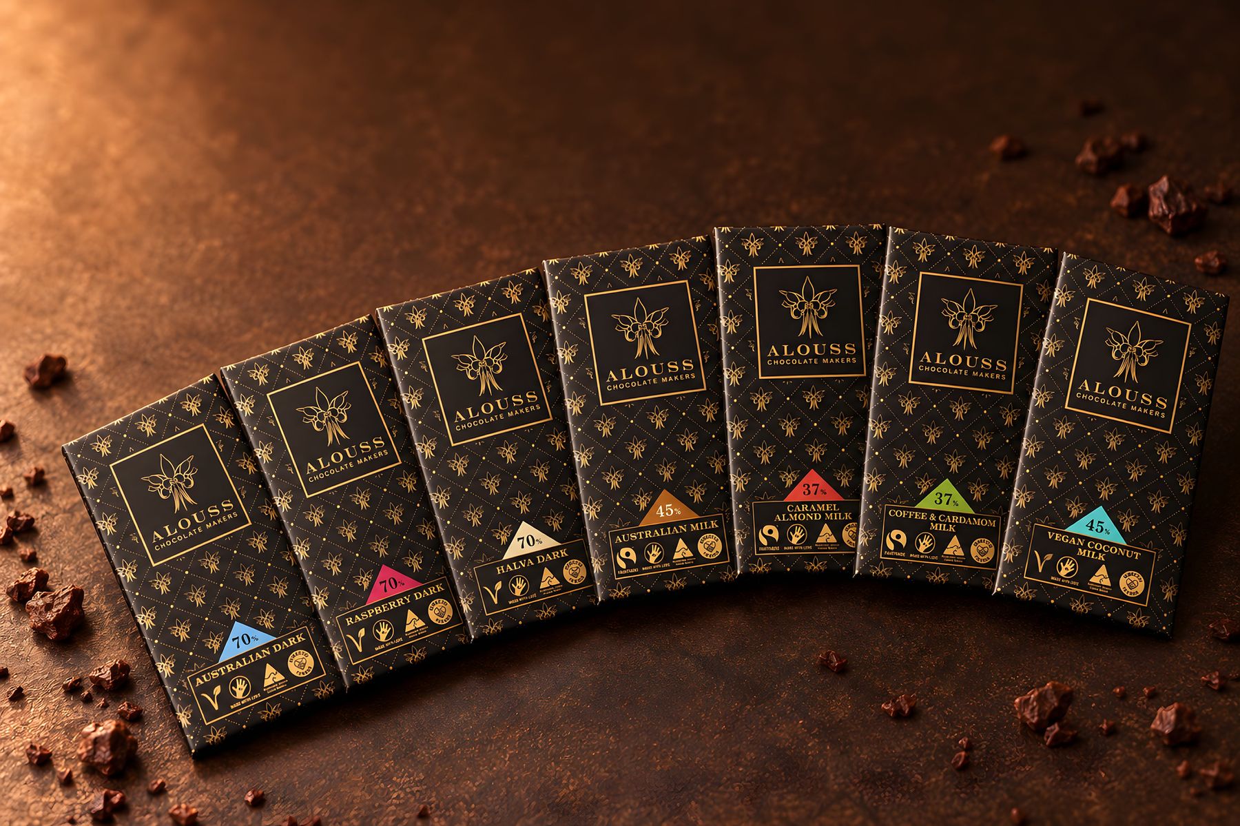 Alouss chocolate bars in black and gold packaging, laid out on a warm cocoa-brown surface